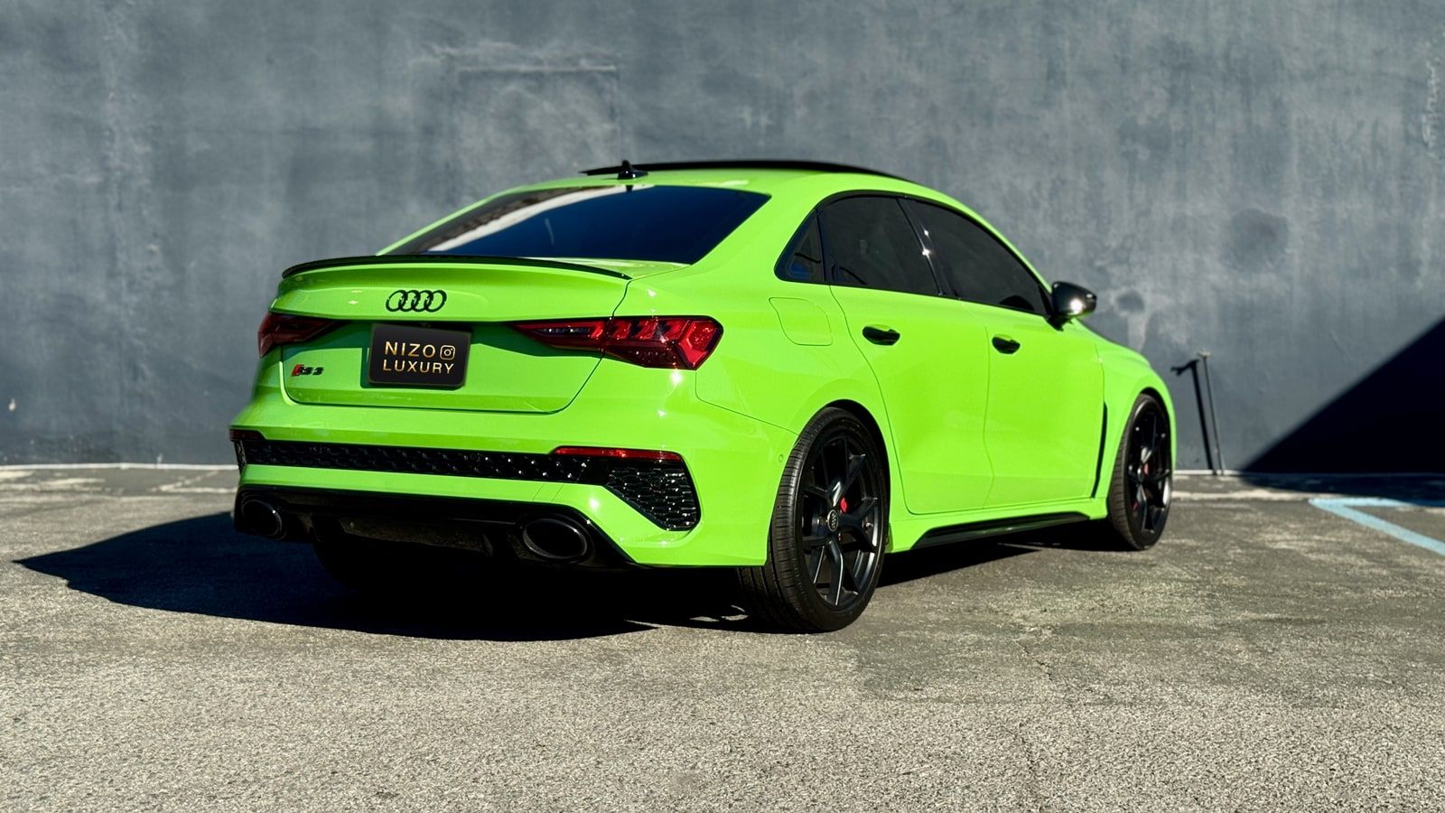 Rear three-quarter of the green Audi RS 3 showing the oval tailpipes