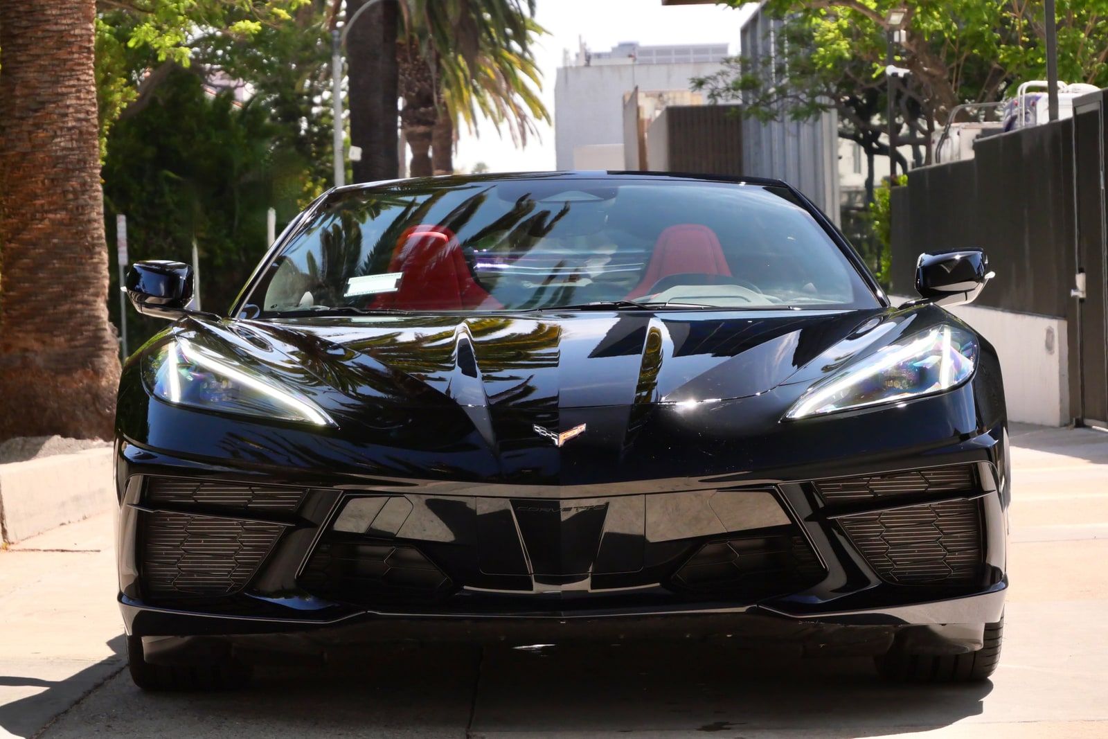 Black Chevrolet Corvette head-on with red seats visible through the windscreen