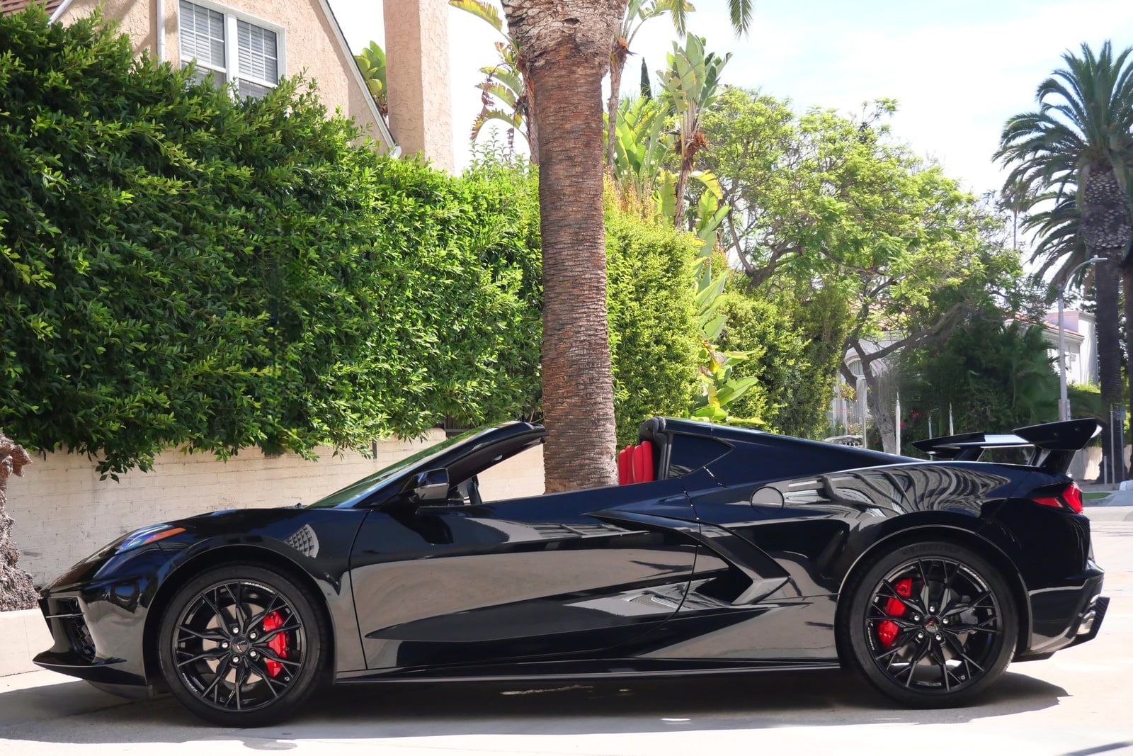 Black Chevrolet Corvette C8 coupe in profile with its removable targa roof panel taken out, parked on a Los Angeles street