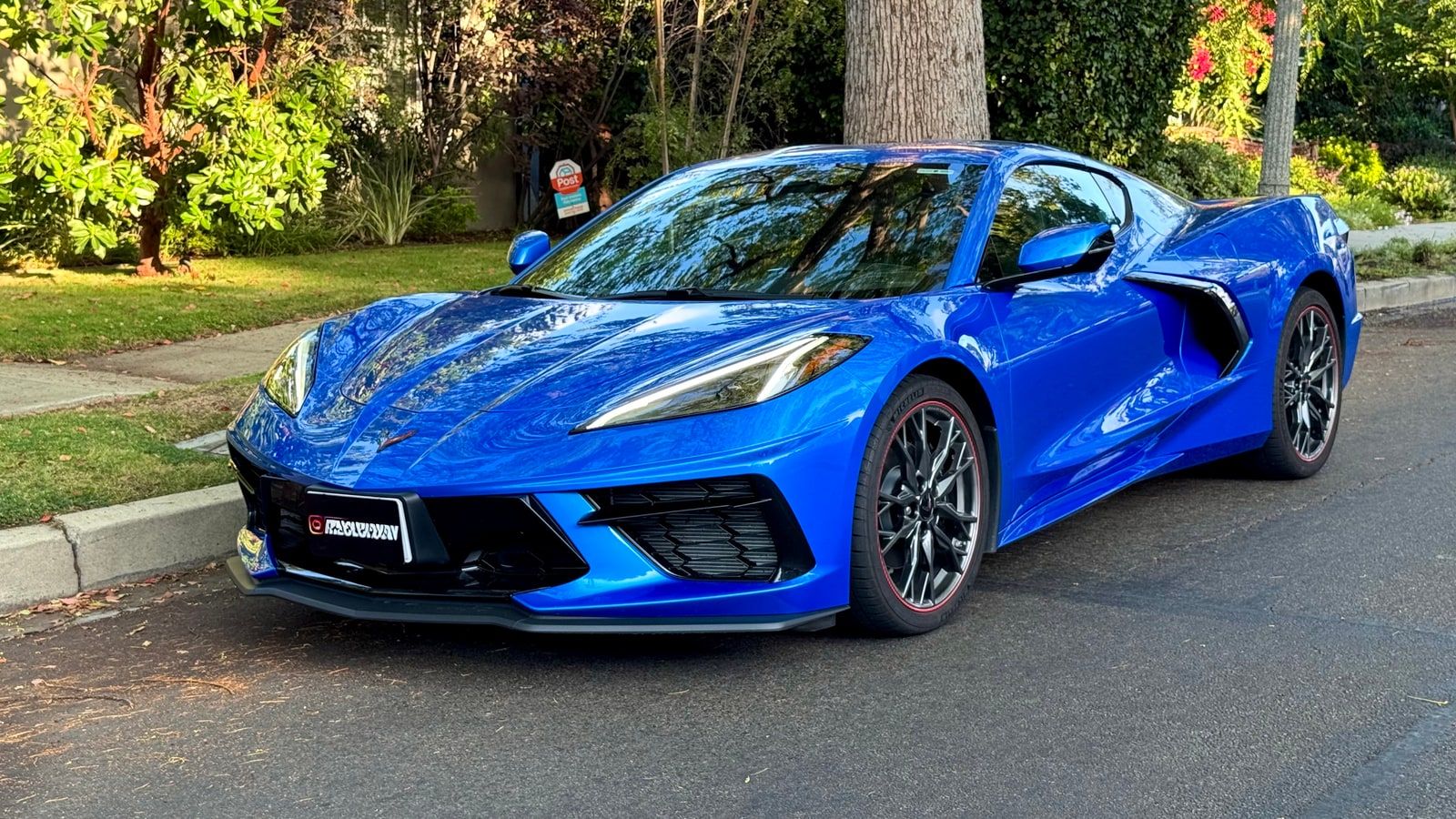 Blue Chevrolet Corvette from a front three-quarter on a residential street