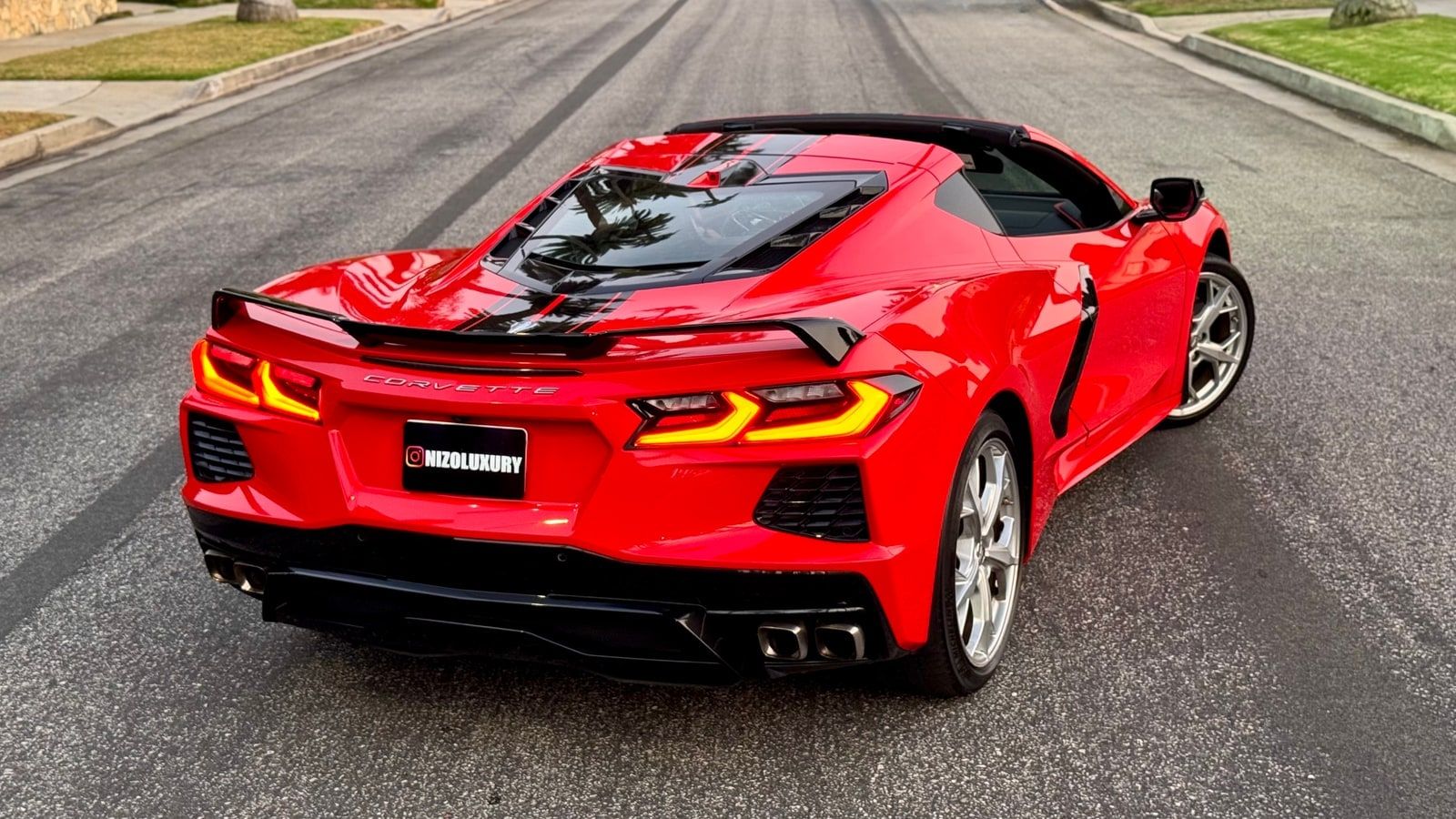 Red Chevrolet Corvette C8 convertible from the rear three-quarter with the hardtop down and the solid rear deck closed