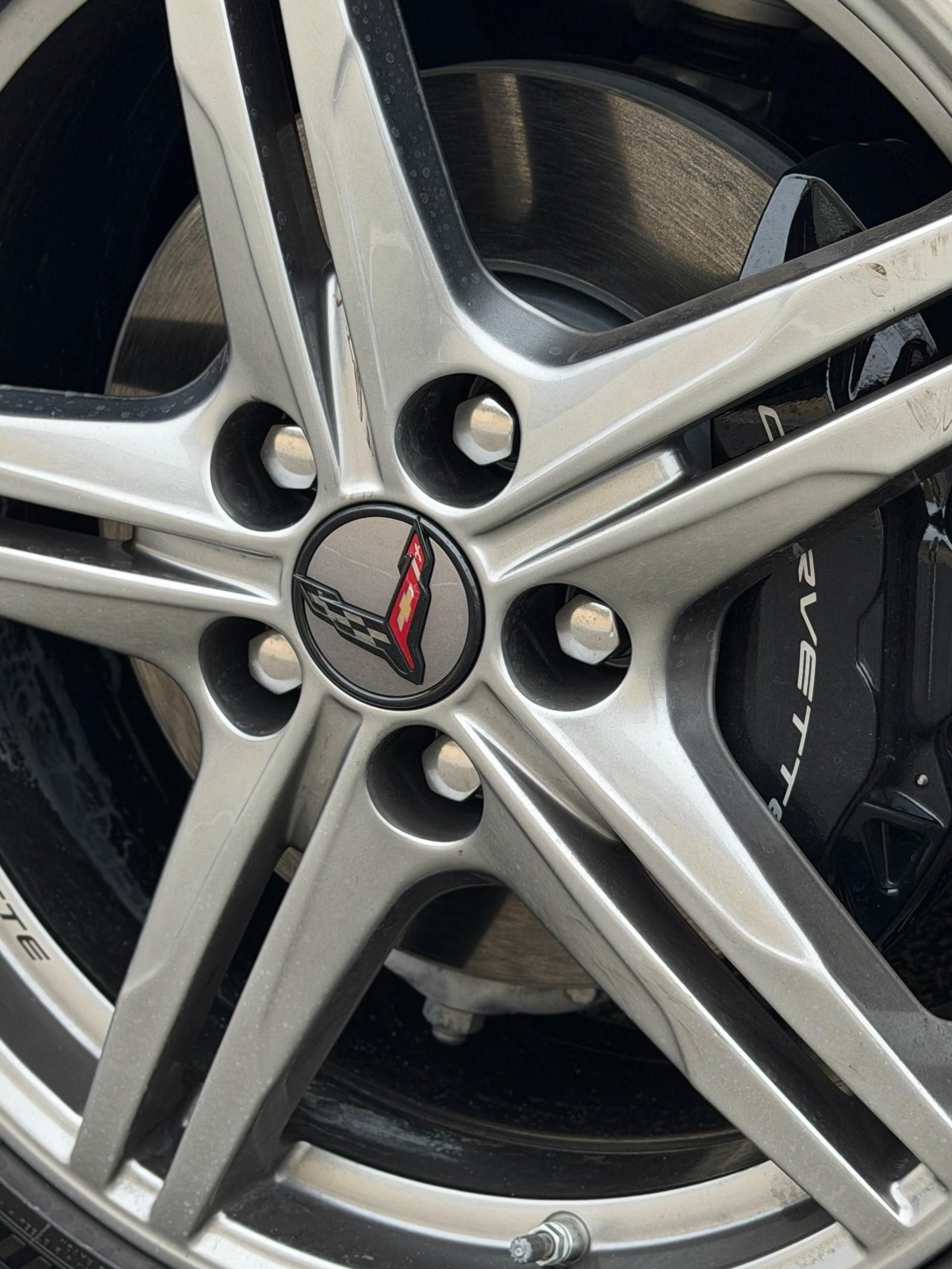 Silver five-spoke wheel and brake of the yellow Chevrolet Corvette