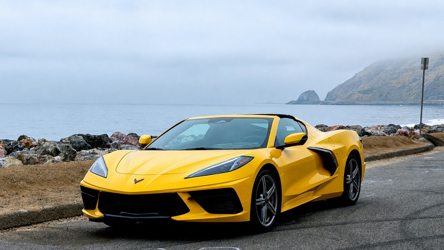 Yellow Chevrolet Corvette C8 with the roof panel off on a coast road