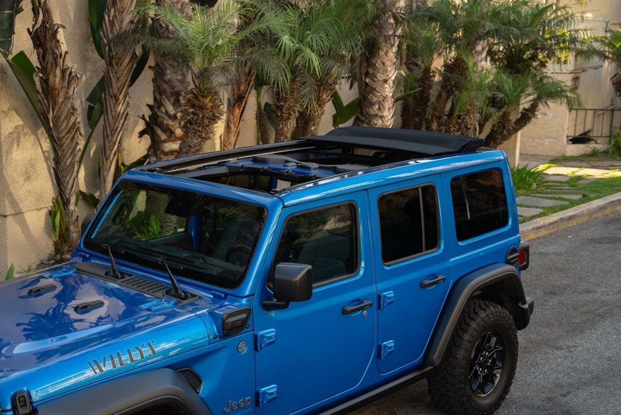 Blue Jeep Wrangler four-door with its roof panels removed on a Los Angeles street