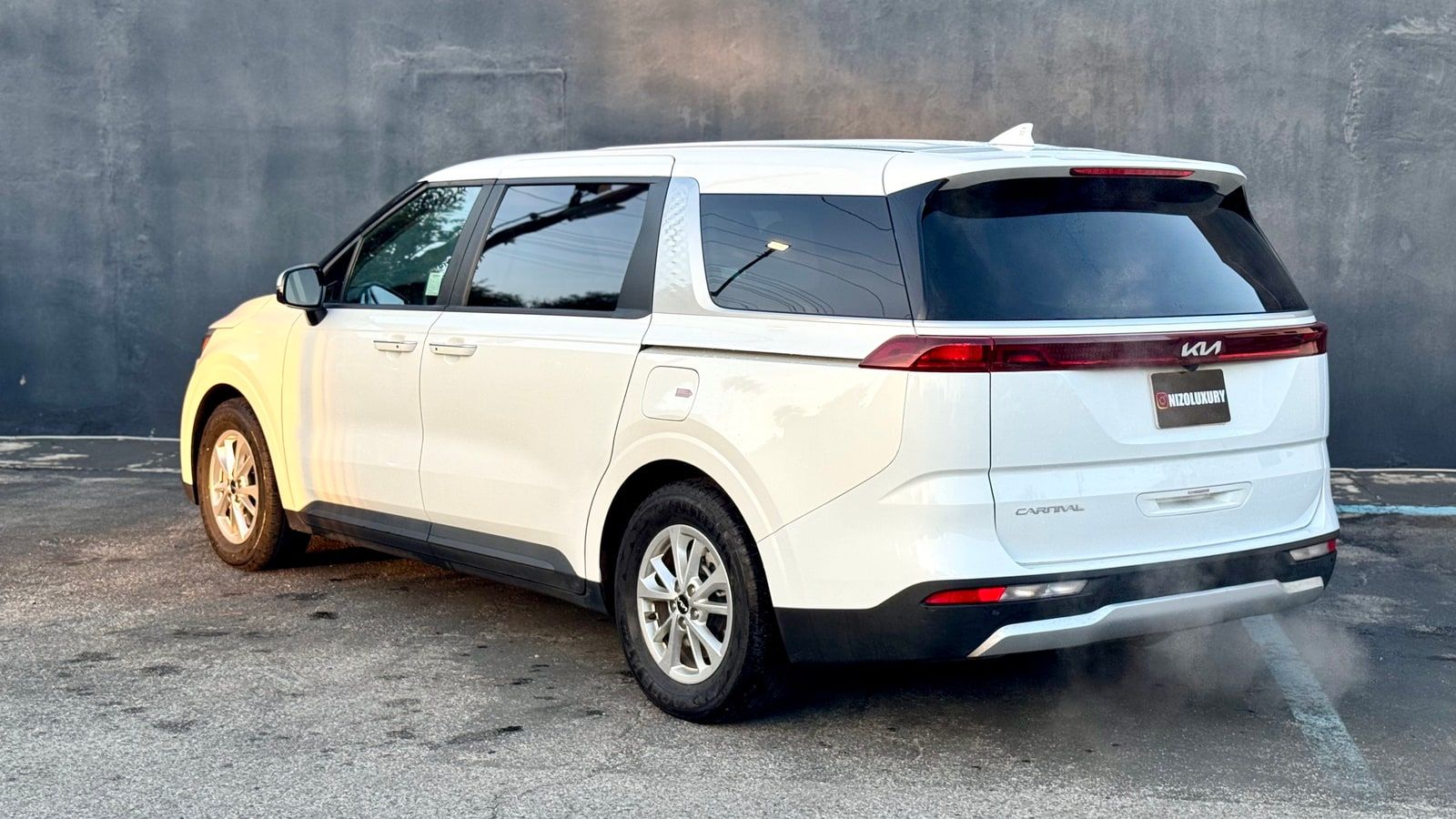 White Kia Carnival minivan with its sliding rear door open on a Los Angeles street