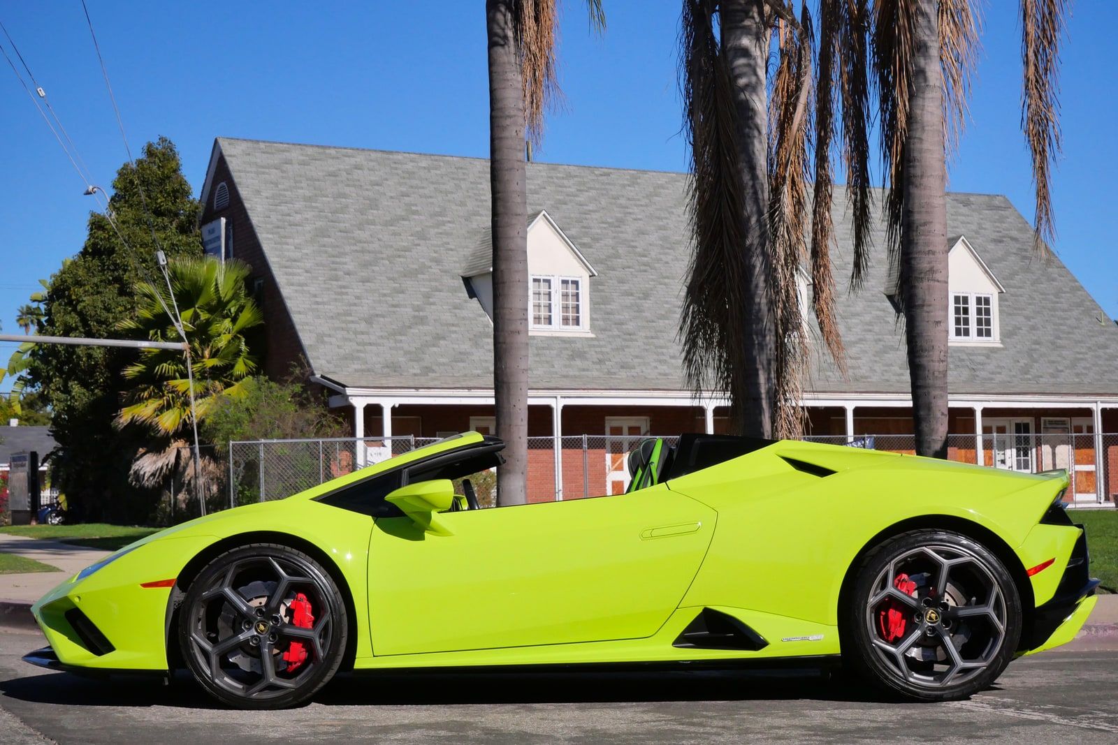 Green Lamborghini Huracán Evo Spider in side profile with the roof stowed on a Los Angeles street