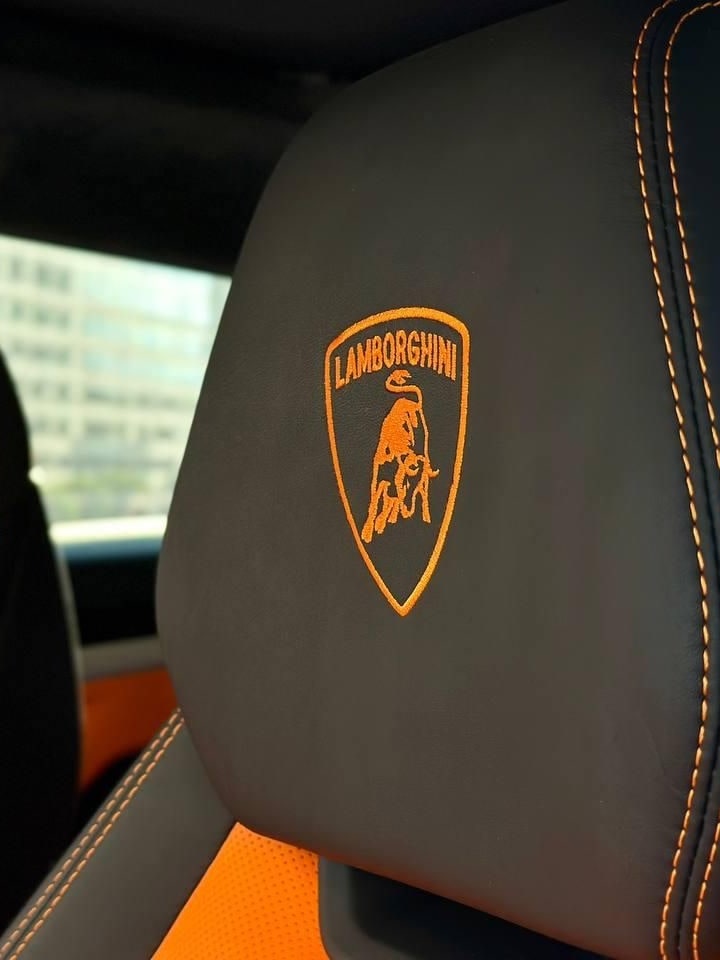 Lamborghini bull stitched in orange on a black headrest