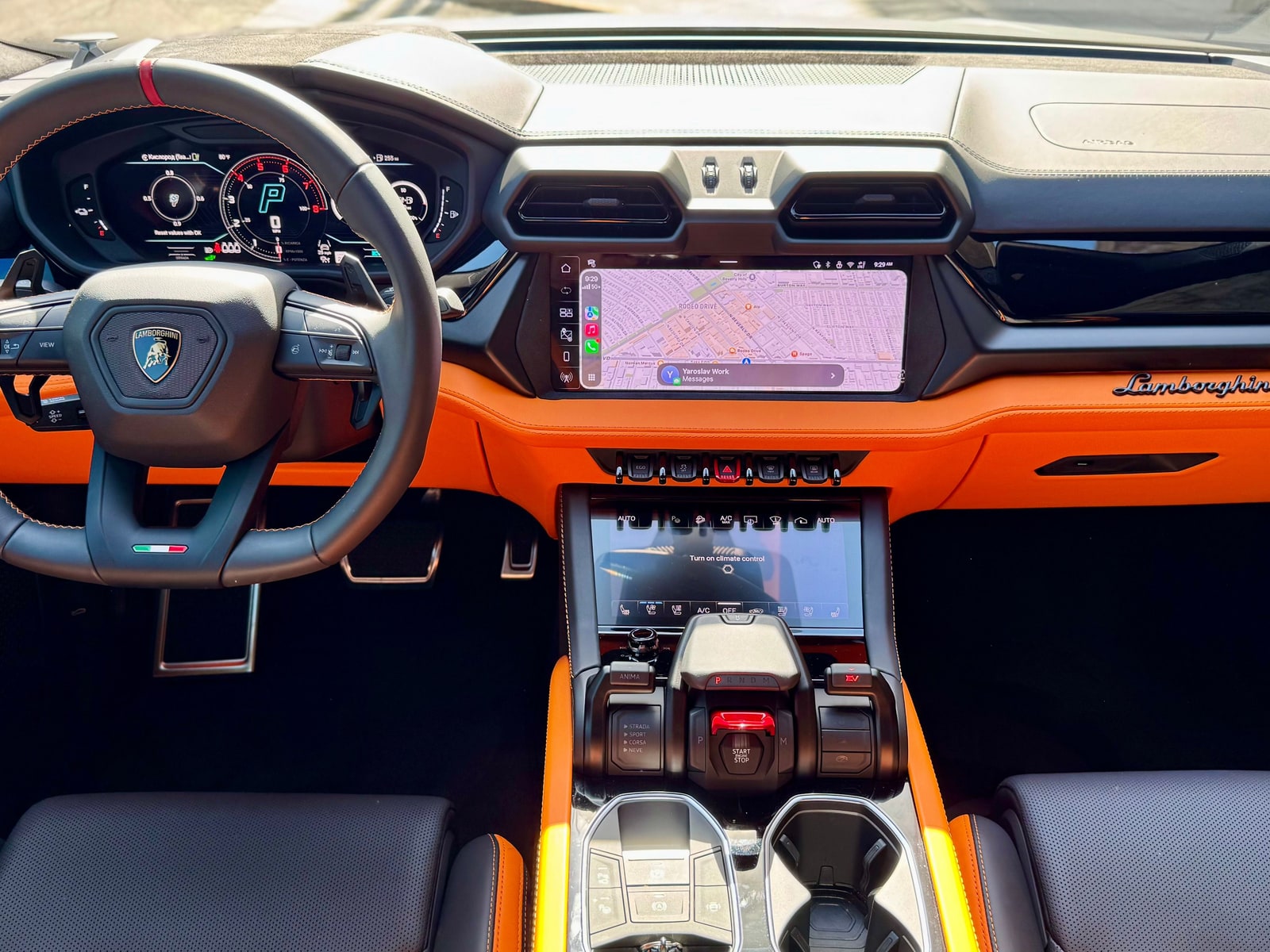 Cockpit of the Lamborghini Urus SE with orange leather, the larger central screen and the drive-mode switches on the console