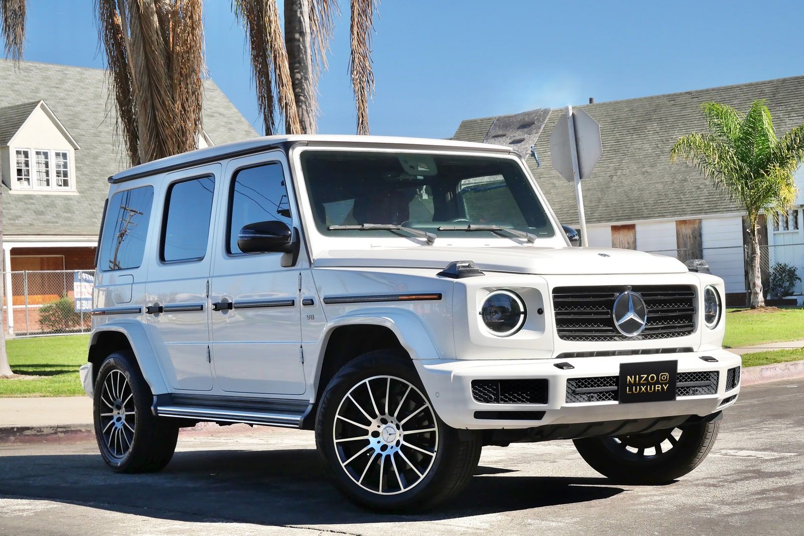 White Mercedes-Benz G 550 from the rear three-quarter with the spare wheel on the tailgate
