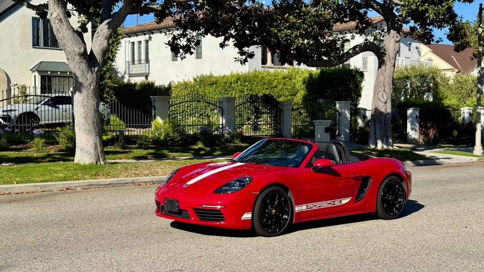 Red Porsche 718 Boxster convertible in profile on a residential Los Angeles street