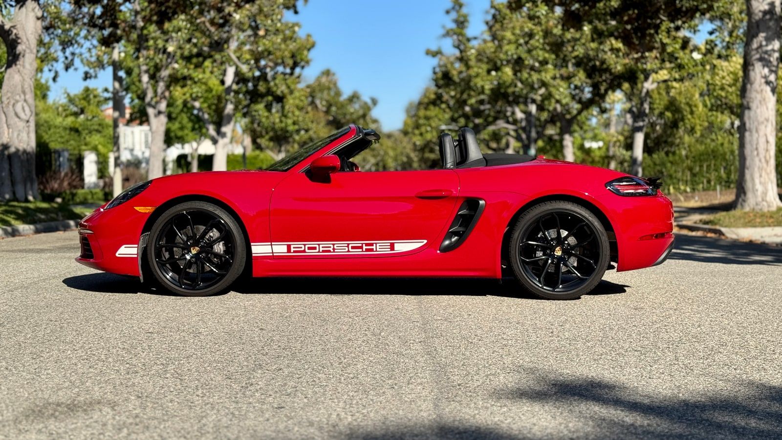 Red Porsche 718 Boxster in profile with the roof down and PORSCHE side script