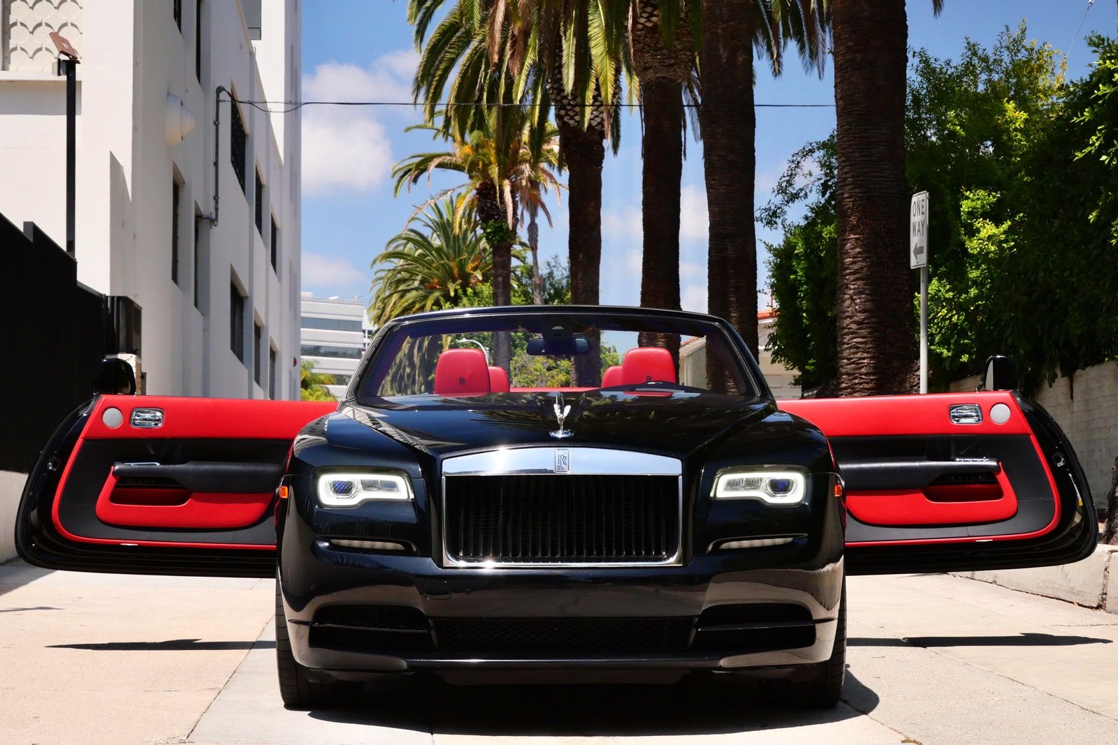Black Rolls-Royce Dawn with the roof down, red leather interior